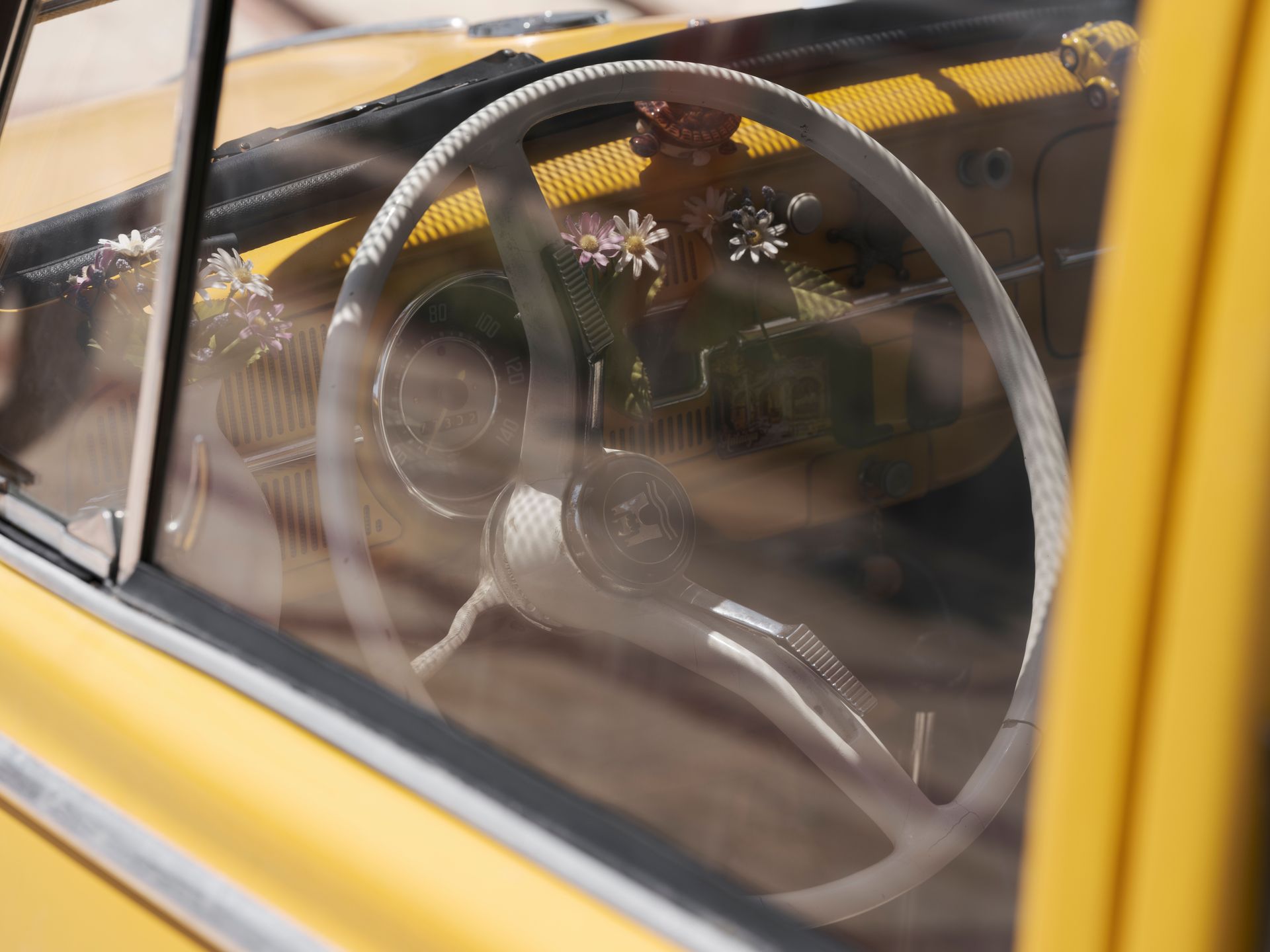 Close-up of a classic yellow car interior showcasing a retro steering wheel and dashboard.