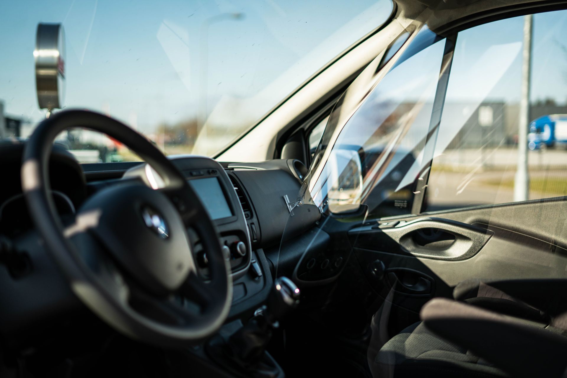 Interior view of a modern car highlighting luxury and design with sunlight reflections through the windshield.