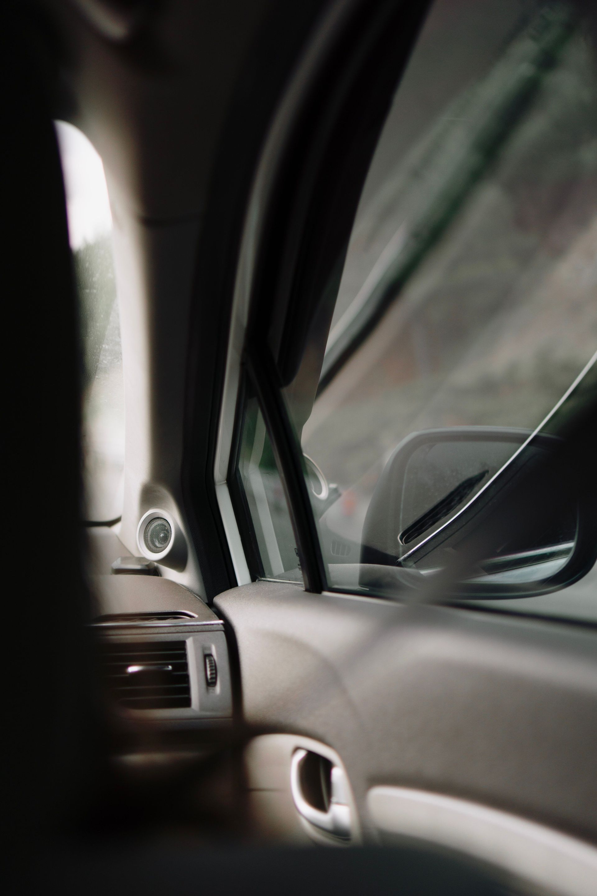 Interior car view focusing on the side window and rearview mirror.